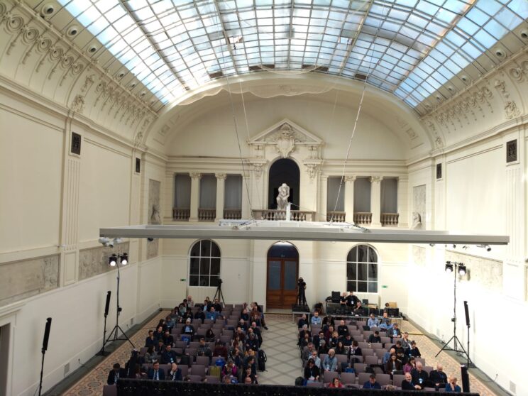 Vista del público sentado escuchando una presentación en un auditorio.