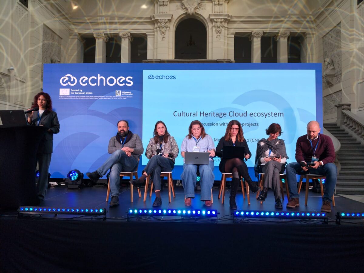 Panel de tres personas sentadas en el escenario durante una discusión, una de ellas hablando