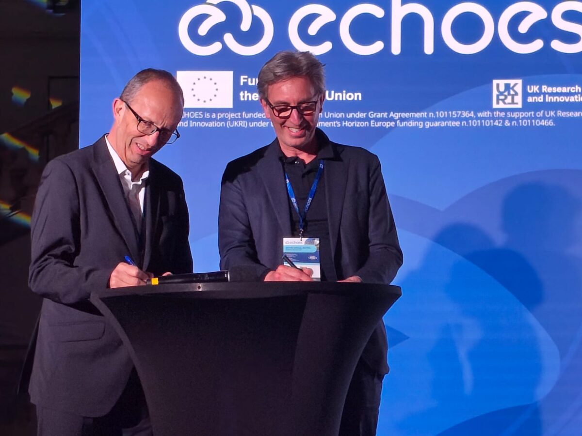 Dos personas firmando un documento en un atril durante una presentación en el evento.